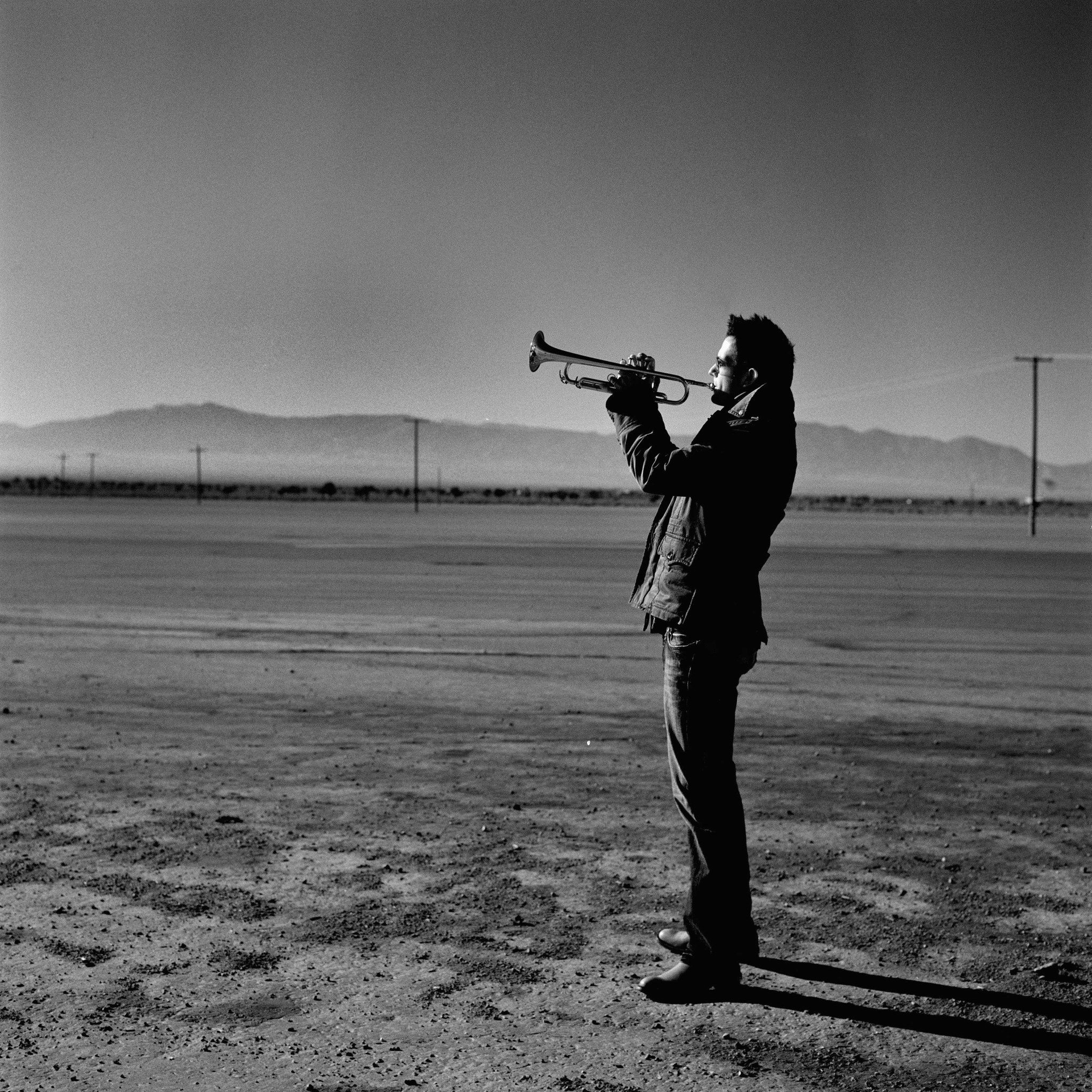 Till playing trumpet in desert, facing left